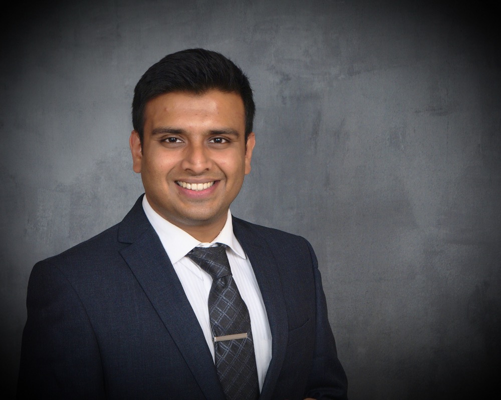 Dr. Abhinit Shah smiling in a dark suit