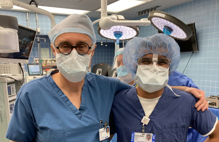 Dr. Shah and a colleague in surgical scrubs and masks in an operating room