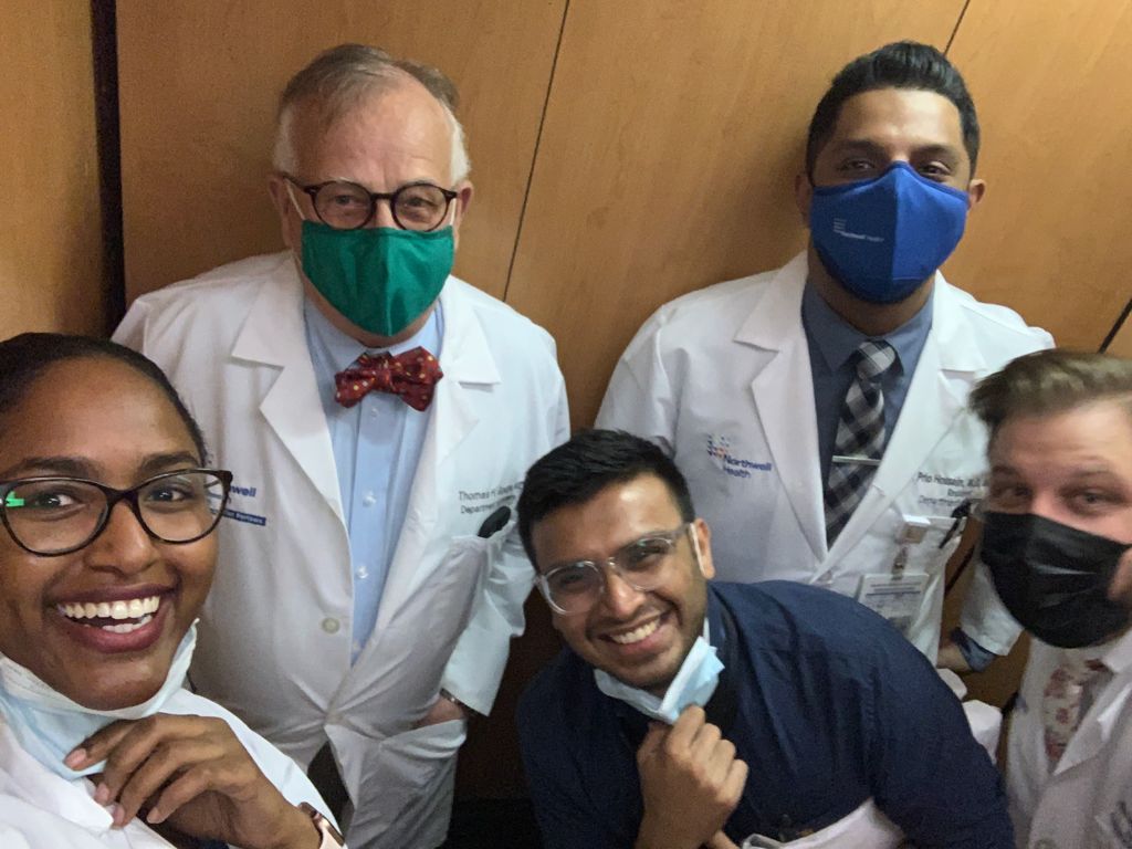 Dr. Shah smiling with a group of colleagues in white coats